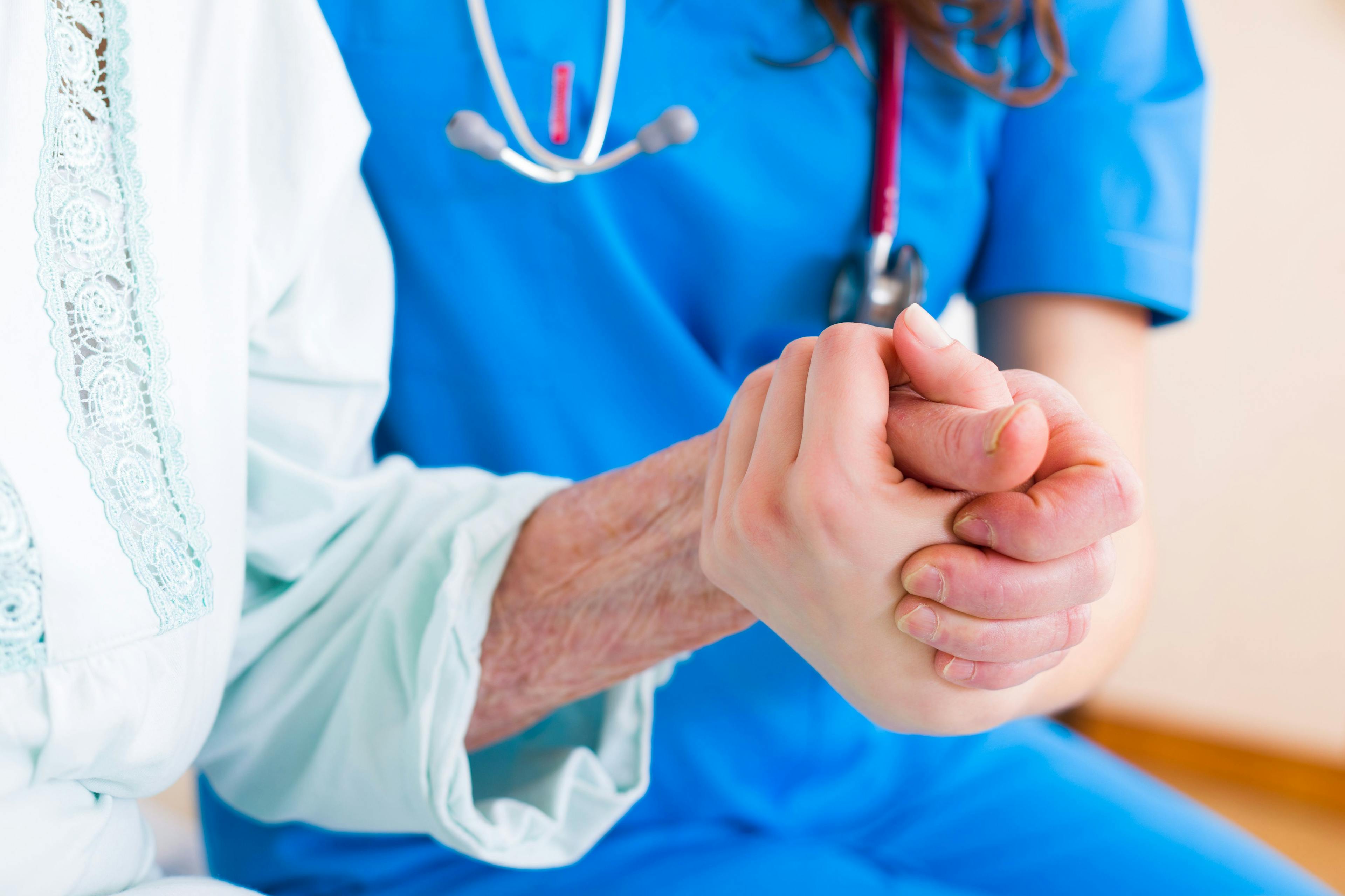 An older patient holding hands with a doctor.