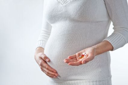 A pregnant woman holding pills and vitamins in her hand