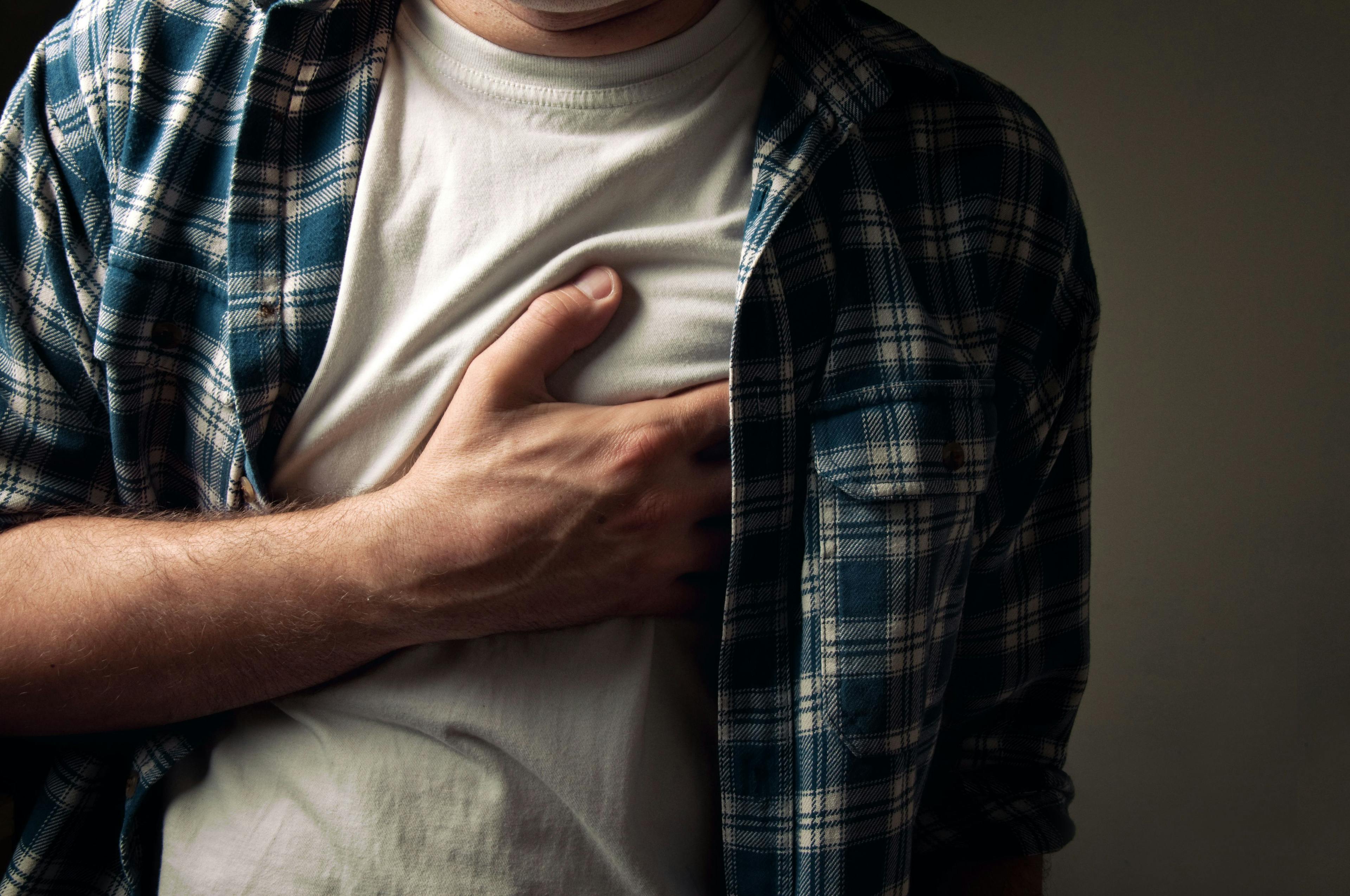 A man gripping his chest due to heart pain.