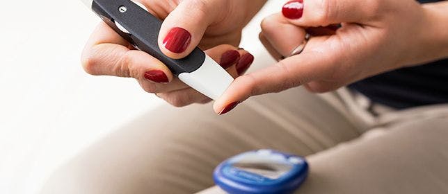 A woman checking her blood sugar with a glucose meter.