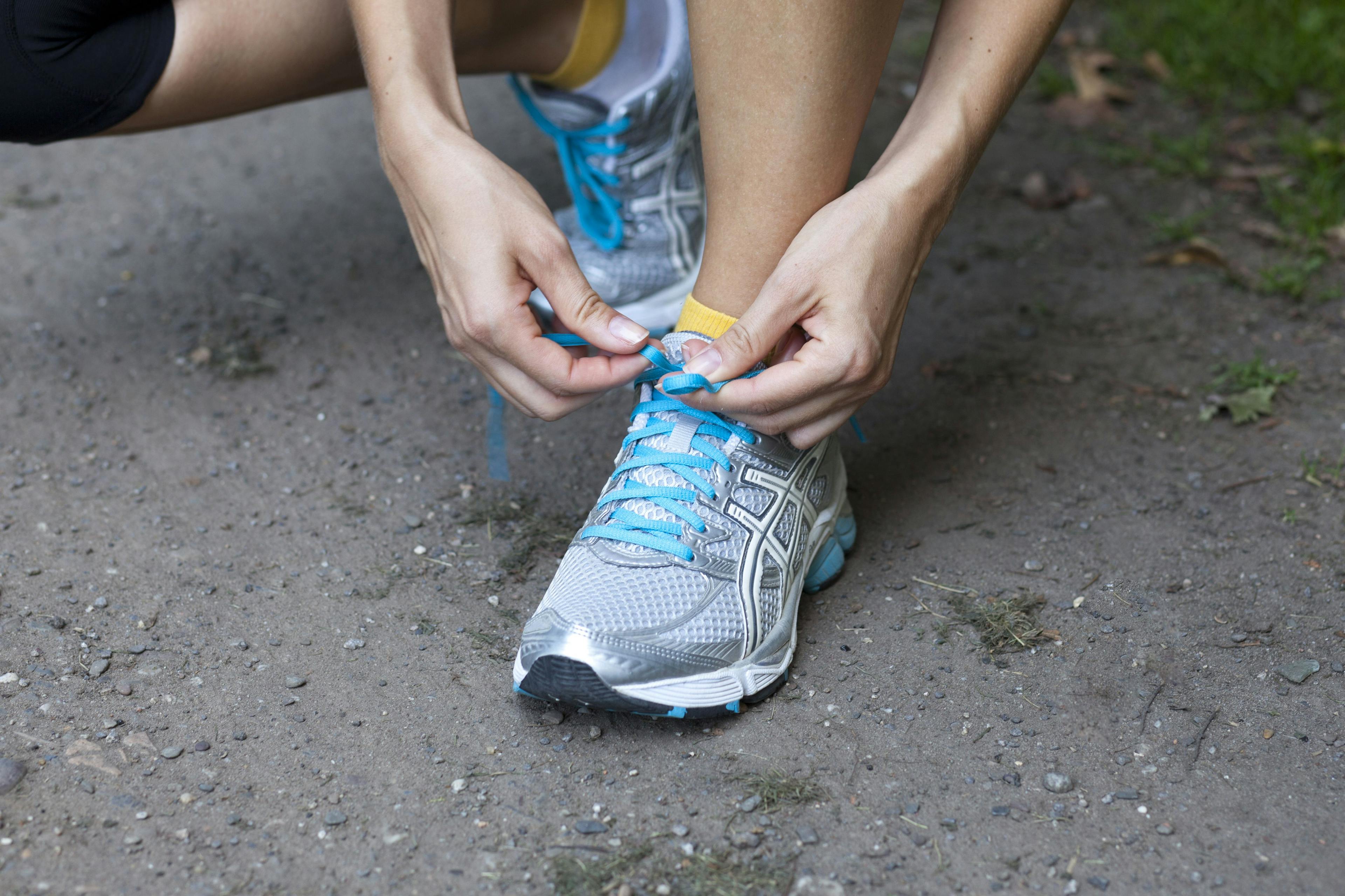 A person with type 1 diabetes tying their shoes before a run.