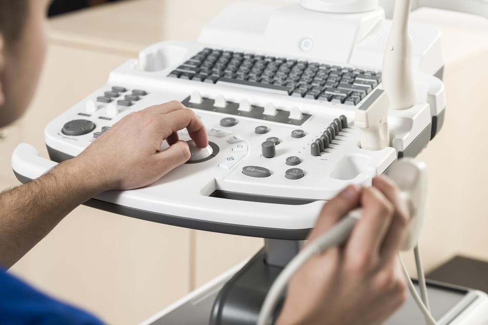 Close-up of a doctor's hands as he prepares an ultrasound machine for use.