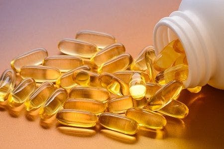 Stock image depicting vitamin D supplements spilling out of a container.