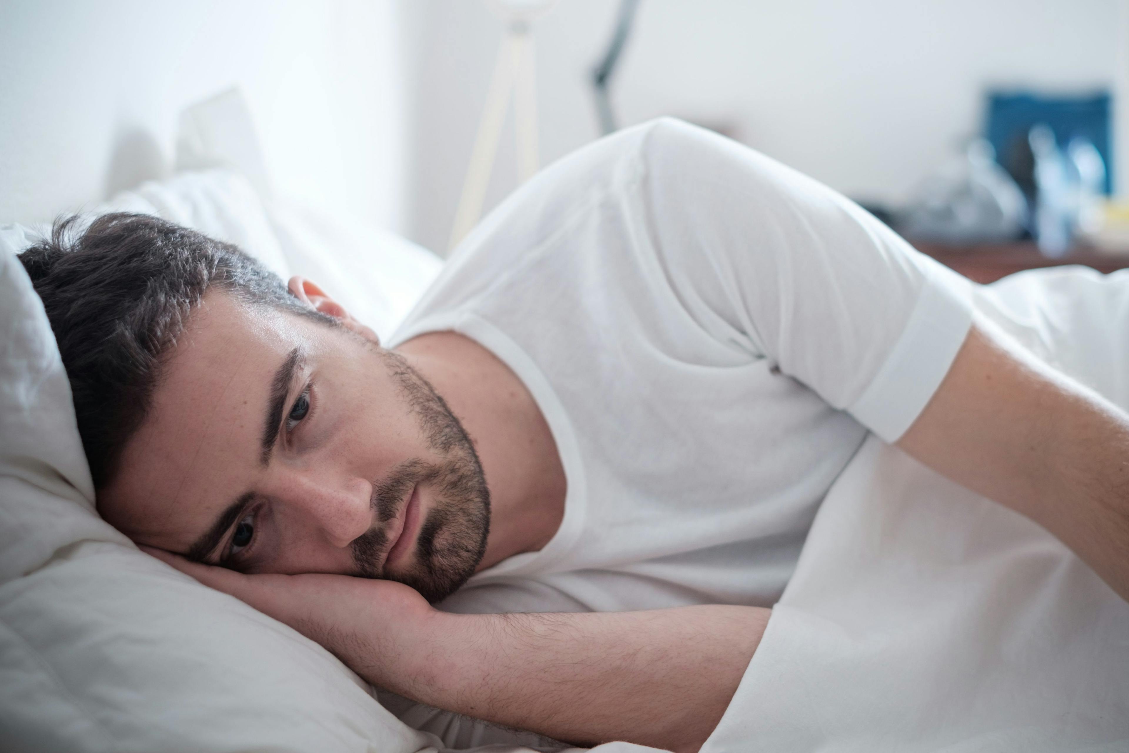 Man laying in bed struggling to sleep
