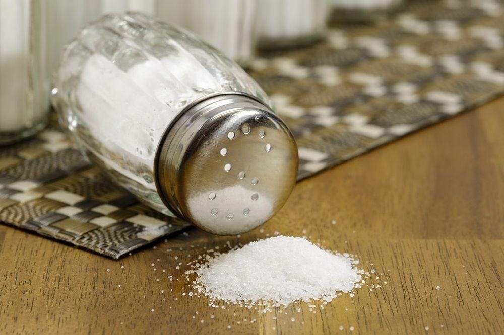 A salt shaker knocked over on a table.