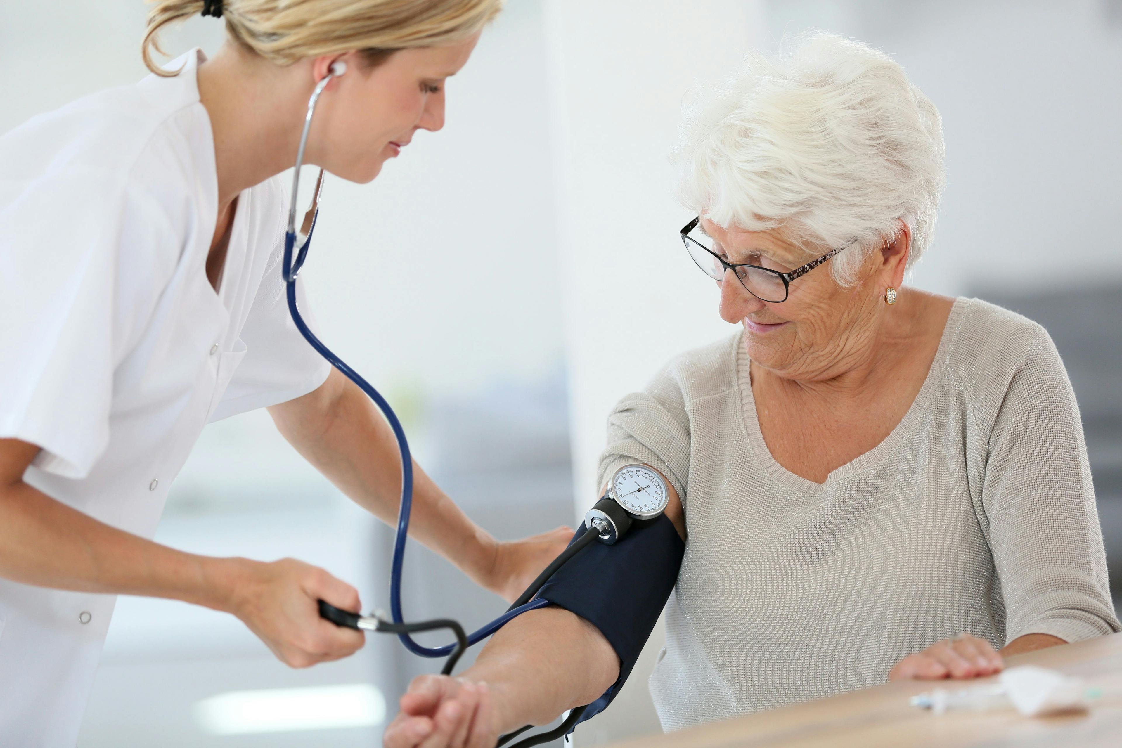 A healthcare provider checking the blood pressure of an older patient.